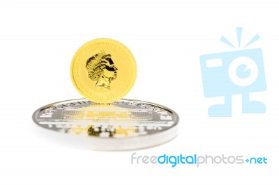 Golden Dollar Coin Standing On Silver Bullion Stock Photo