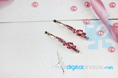 Golden Hairpins With Pink Gemstone And Pink Ribbon And Pink Pearls On White Wood Stock Photo