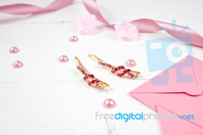 Golden Hairpins With Pink Gemstone And Pink Ribbon On Pink Background Stock Photo