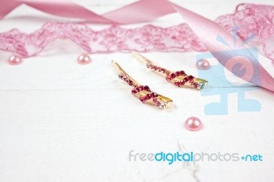 Golden Hairpins With Pink Gemstone And Pink Ribbon On Pink Background Stock Photo