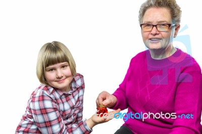 Grandmother Putting Euro Coin In Grandchild's Piggy Bank Stock Photo