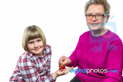 Grandmother Putting Euro Coin In Grandchild's Piggy Bank Stock Photo