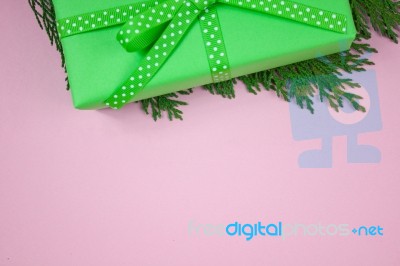 Green Gift With Polka Dot Ribbon And Cypress On Pink Background Stock Photo