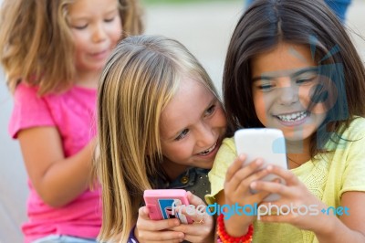 Group Of Childrens Chatting With Smart Phones In The Park Stock Photo