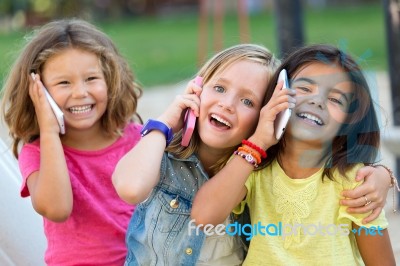Group Of Childrens Using Mobile Phones In The Park Stock Photo