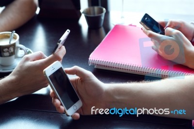 Group Of Friends Using Mobile Phone In Cafe Stock Photo