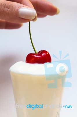 Hand Dips A Cherry In Yogurt Stock Photo