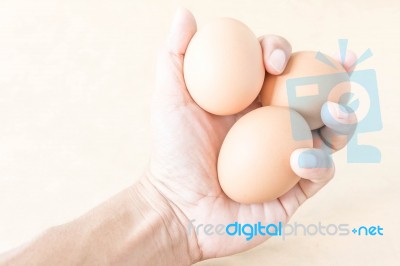 Hand Holding An Eggs On Brown Background Stock Photo