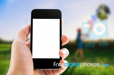 Hand Holding Smart Phone Against Woman Background Stock Photo