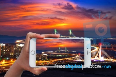 Hand Holding Smart Phone Take A Photo At Incheon Bridge With Sunset Stock Photo