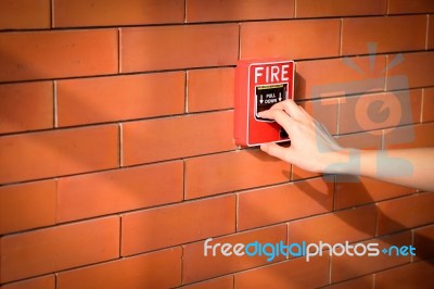 Hand Of Woman Is Pulling Fire Alarm On The Brick Wall Stock Photo