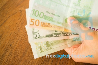 Hand On Nternational Currencies Bank Note On Wooden Table Stock Photo