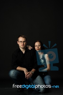 Handsome Young Couple Posing Sitting In Studio Stock Photo