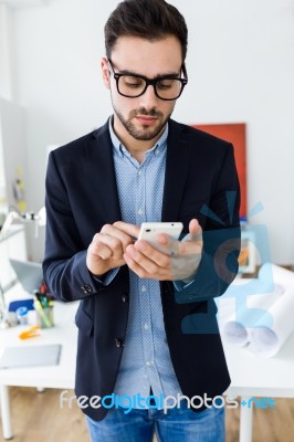 Handsome Young Man Using His Mobile Phone In The Office Stock Photo