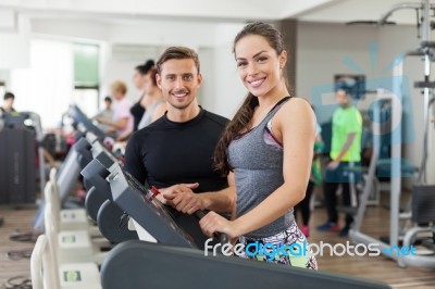 Happy Coach Assisting Young Woman In A Gym Stock Photo