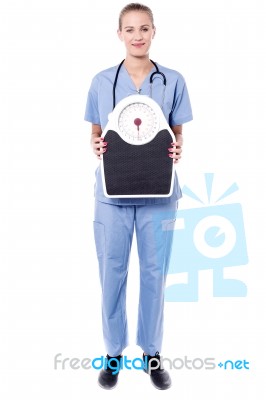 Happy Doctor Holding A Weight Scale Stock Photo