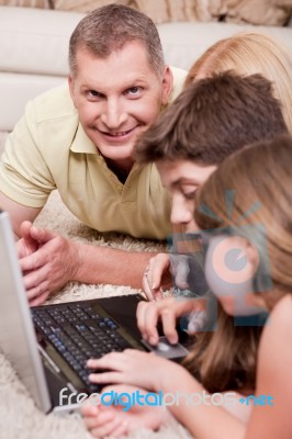 Happy Family Lying And Working With Lap Top Stock Photo