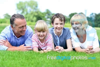Happy Family Lying On Lush Green Grassland Stock Photo