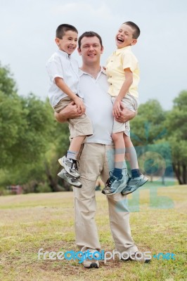 Happy Father Carrying His Two Son In His Hands Stock Photo