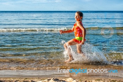 Happy Little Girl Making Splashes On The Beach Stock Photo