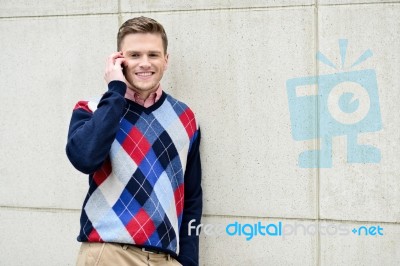 Happy Man Leaning Against Wall With Cell Phone Stock Photo