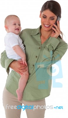 Happy Mother Carrying Son While Using Mobile Phone Stock Photo