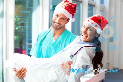 Happy Surgeon Carrying Female Doctor During Christmas Stock Photo