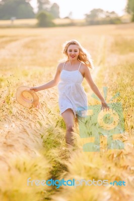 Happy Young Blonde Girl In White Dress With Straw Hat Running Th… Stock Photo