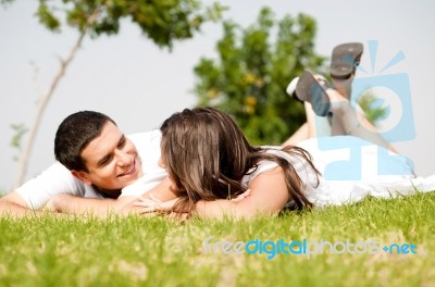 Happy Young Couple Lie Down On Grass Stock Photo
