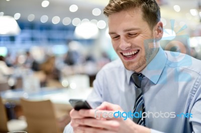 Happy Young Executive Sitting With Smartphone Stock Photo