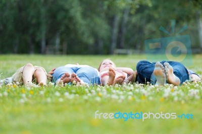 Happy Young Family Lying On Grass Stock Photo