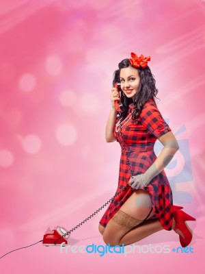 Happy Young Pinup Kneeling Woman Talking On Phone Stock Photo
