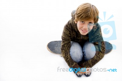 High Angle View Of Boy Sitting On Skateboard Stock Photo