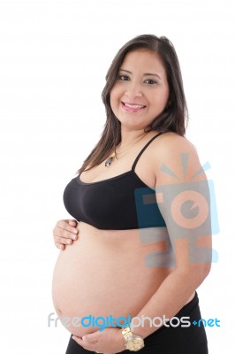 Hispanic Pregnant Woman Smiling And Touching Her Belly Stock Photo