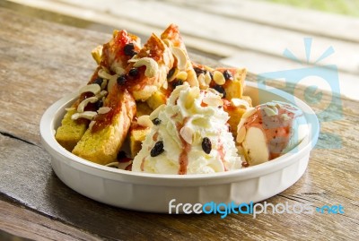 Homemade Ice Cream Dessert With Toasts, Raisins, Cashew Nuts, And Whip Cream In White Ceramic Bowl Stock Photo