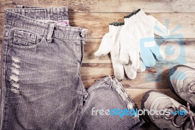 Jeans And Sneakers With Gloves On A Wood Background Stock Photo