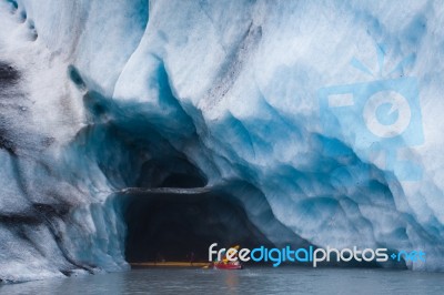 Kayaking Into Blue Ice Cave Stock Photo