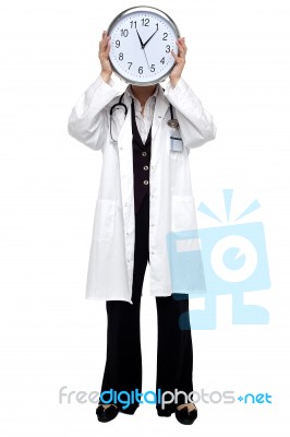 Lady Doctor Holding Clock Before Her Face Stock Photo