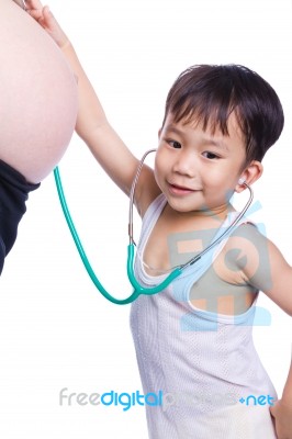 Little Asian Boy Examining Pregnant Mother's Tummy Stock Photo
