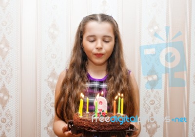 Little Girl Blowing Out Candles On The Cake Stock Photo