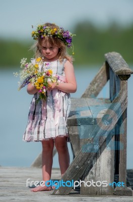 Little Girl With Flowers On A Bridge Stock Photo