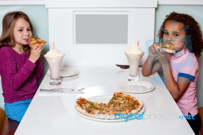 Little Girls Enjoying Pizza In A Restaurant Stock Photo