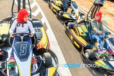 Little Girls Preparing To Drive  Go- Kart Car In A Playground Racing Track Stock Photo