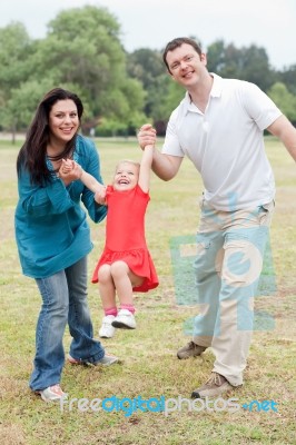Lovely Couples Playing With Their Happy Daughter At The Park Stock Photo