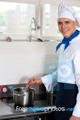 Male Cook Prepares A Dish In The Kitchen Stock Photo