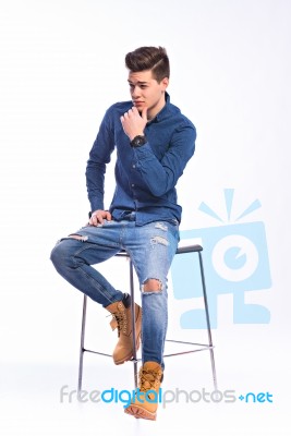 Male Model In Denim Jeans Sitting On A Chair . Studio Shoot Stock Photo