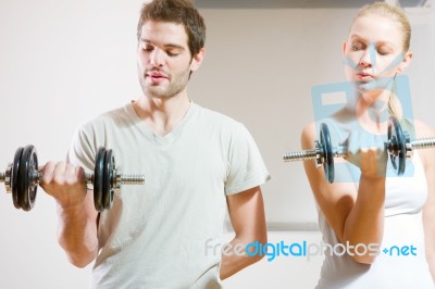Man And Woman Lifting Dumbbell In Gym Stock Photo