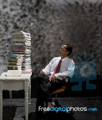 Man Looking To Big Stack Of Book On Working Table Stock Photo