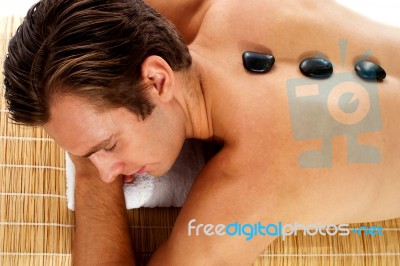 Man Relaxing With Spa Stone Stock Photo