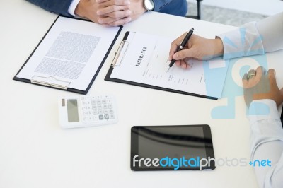 Man Signing A Car Insurance Policy, The Agent Is Holding The Doc… Stock Photo